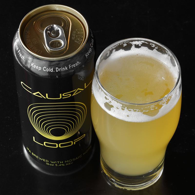 Causal Loop cans next to a poured glass