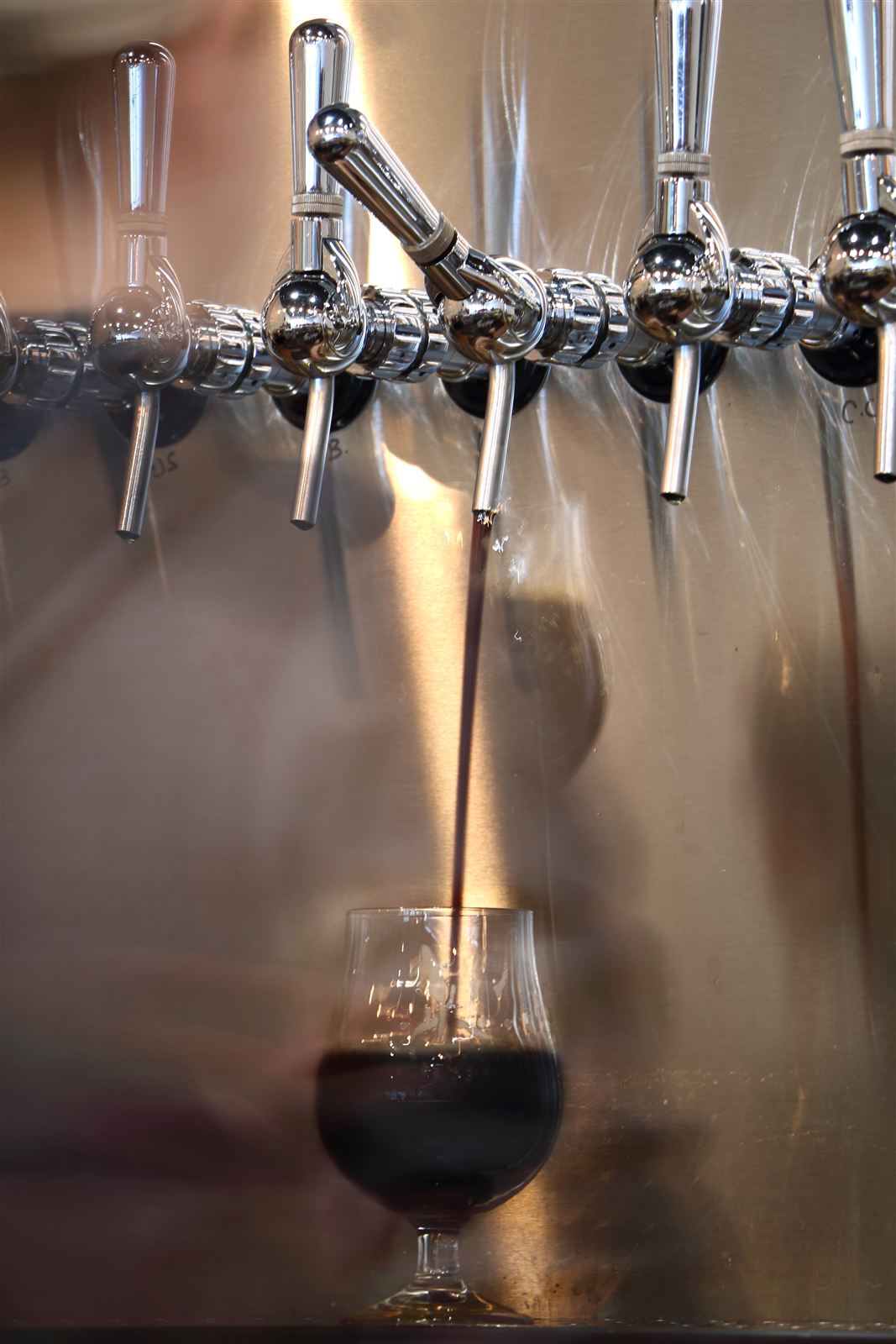 A dark beer pouring from a row of taps